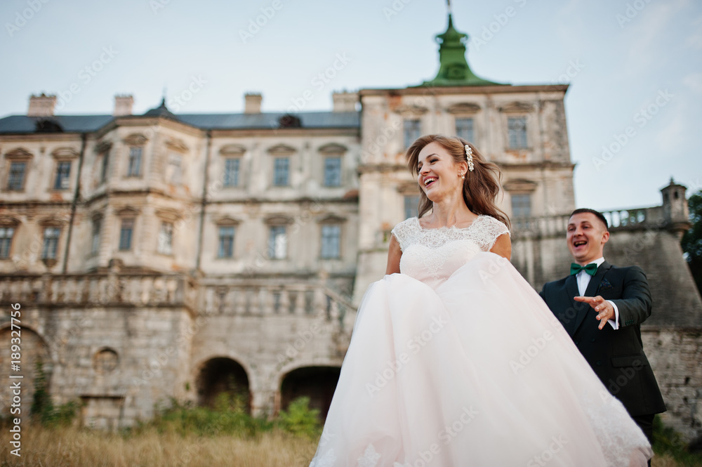 Fabulous wedding couple posing in front of an old medieval castle in the countryside on a sunny day.