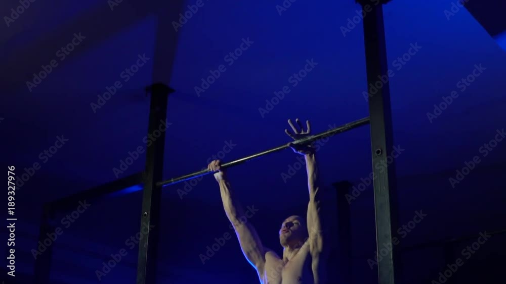 A muscular man pulls up to his chest on the crossbar.Close-up. Slow motion A muscular man pulls up to his chest on the crossbar.Close-up. Slow motion