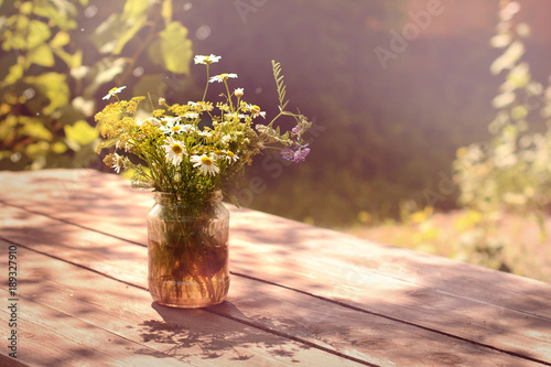 Photos Beautiful bouquet of wildflowers on wooden table in rays of evening sun