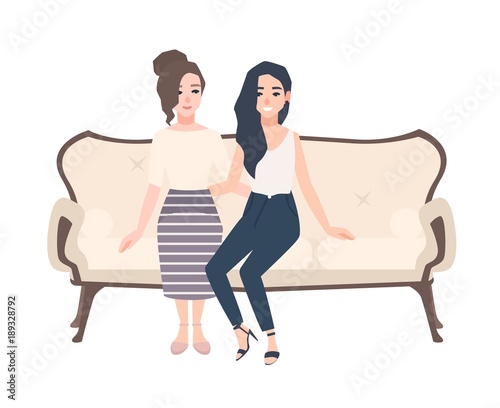 Pair of smiling young women dressed in elegant clothes sitting on classical s...
