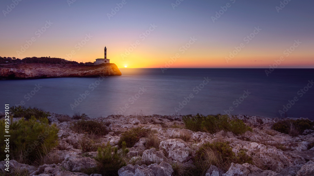 Lighthouse in Portocolom, Mallorca, spanish island. Sunrise on the blue mediterranean sea.