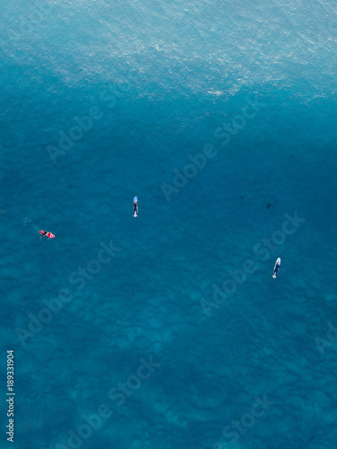 Aerial view of groups of surfers in the water.