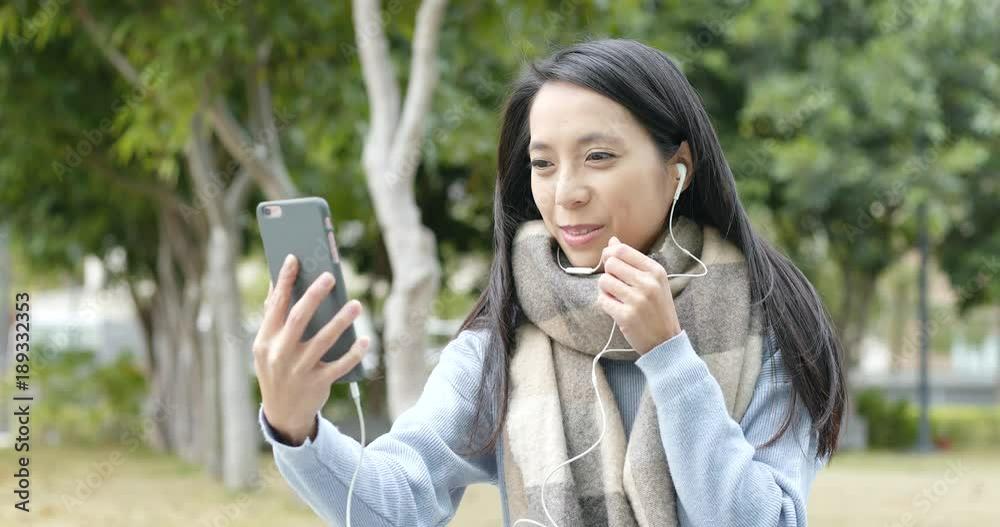 Woman talk to video call on cellphone with earphone at outdoor Woman talk to video call on cellphone with earphone at outdoor
