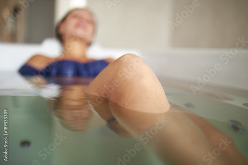 woman relaxing in the bathtub. Female patient receives water procedures in spa salon. Soft focus on knee. Copy space photo