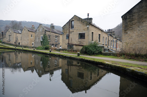 streets of terraced houses alongside the rochdale canal in hebden bridge with buildings reflected in the water in winter photo