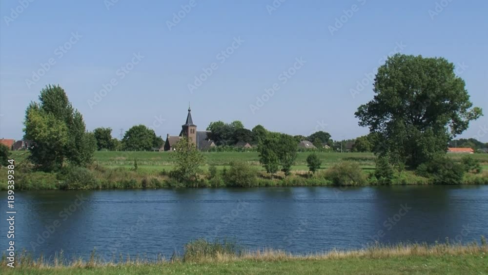 River Meuse (Maas) The Netherlands, church tower and village of Niftrik behind river dike + pan