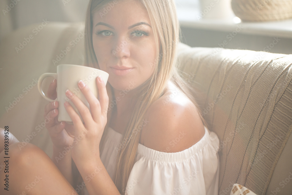 Beautiful young woman relaxing at living room while enjoying in coffee.