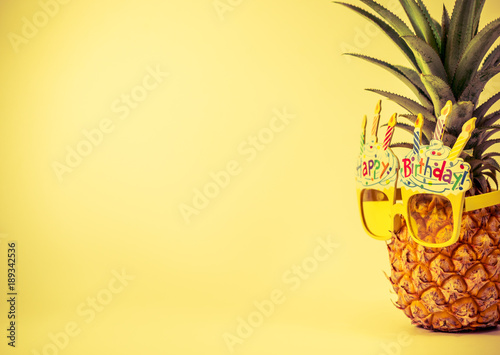yellow fancy glasses on fresh pineapple, copy space on left, summer birthday concept, retro color tone