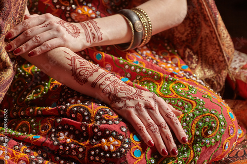 Mehendi on his hands against the backdrop of a national Indian costume. Close-up.