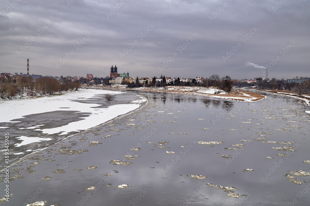 Urban landscape with river Warta and the cathedral towers in winter in Poznan.
