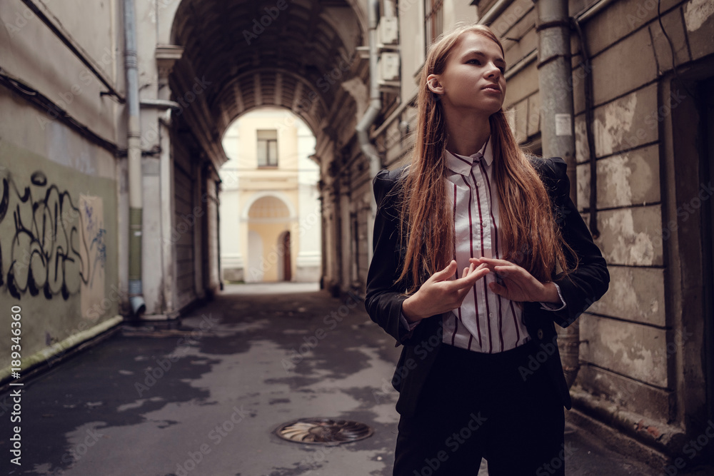 A young red-haired girl in a business suit is walking along a beautiful old town. St.Petersburg