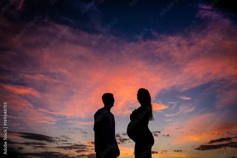 puesta de sol con mujer embarazada y su pareja