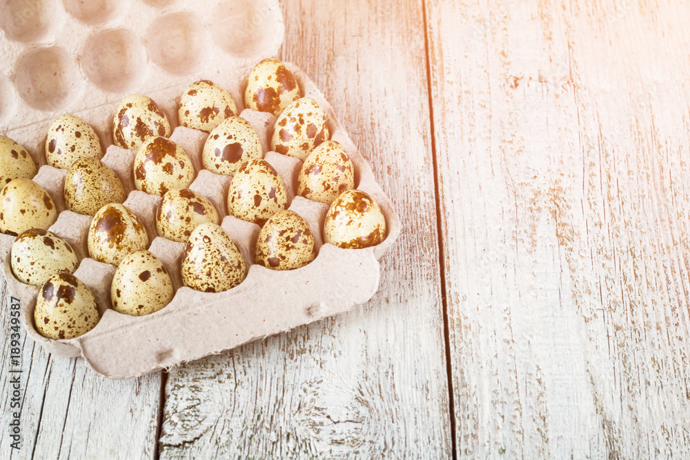 Cardboard egg rack wit quail eggs on white wooden table Cardboard egg rack wit quail eggs on white wooden table