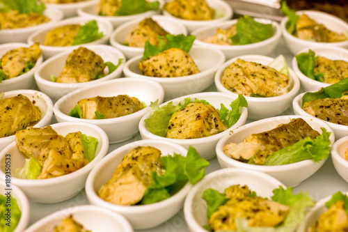 Pieces of white fish grilled, served in white bowls, decorated with lettuce leaves