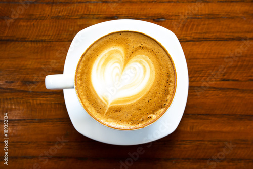 Top view of hot coffee latte cappuccino foam in white coffee cup on wooden table background