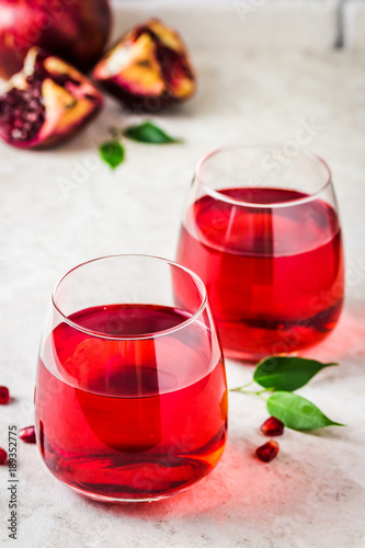 Two glasses with pomegranate juice on white marble background. Selective focus, copy space.