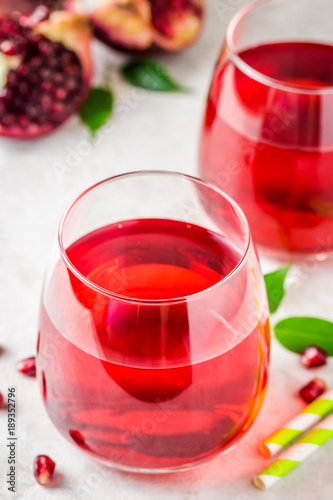 Two glasses with pomegranate juice on white marble background. Selective focus, copy space.