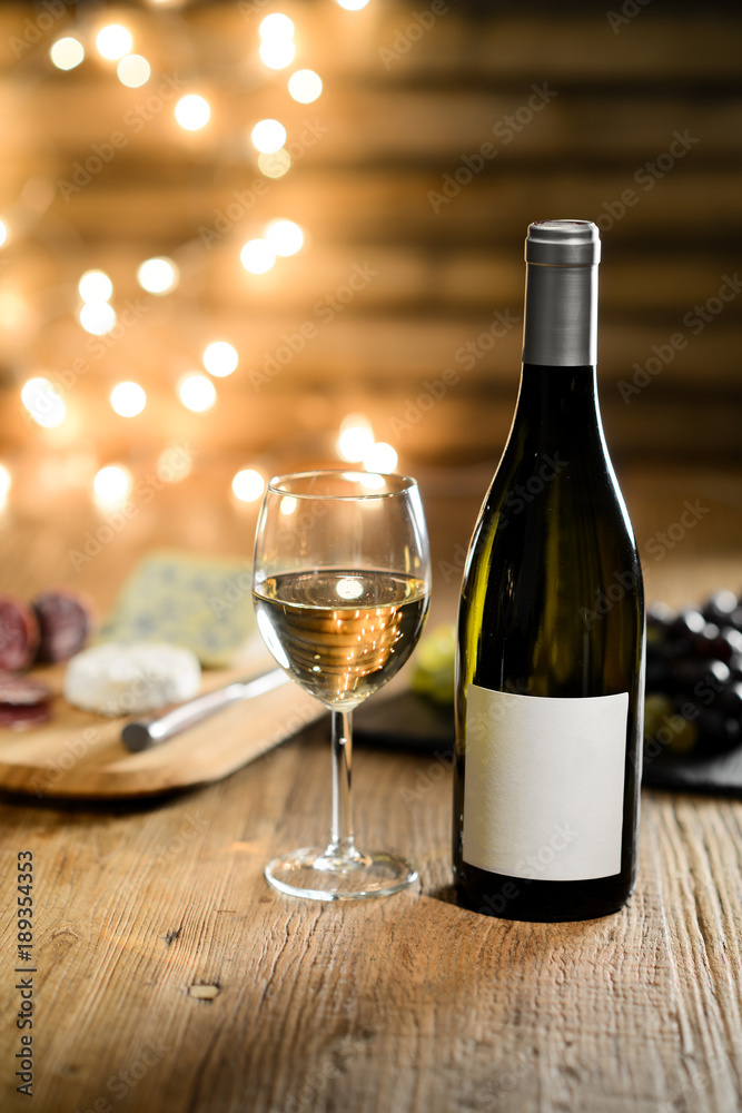 glass of white wine with french cheese and delicatessen in restaurant wooden table with romantic dim light and cosy atmosphere