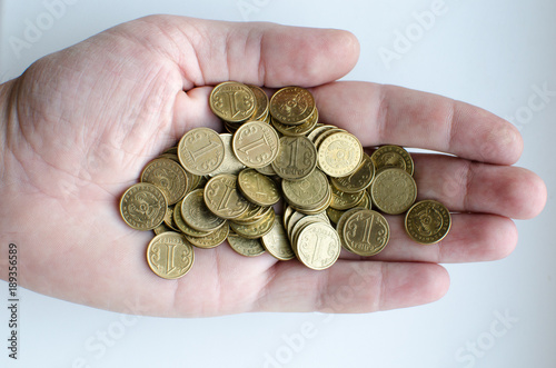 Man hand holding a lot of coins face value of one tenge