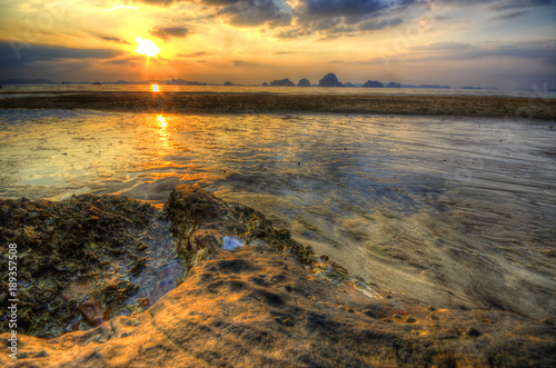 Sunset over the beach in Krabi, with orange sunlight reflecting in the surf