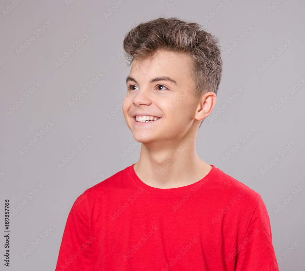 Close up emotional portrait of caucasian teen boy. Handsome smiling guy. Funny cut teenager on gray background. Child looking away. Close up emotional portrait of caucasian teen boy. Handsome smiling guy. Funny cut teenager on gray background. Child looking away.