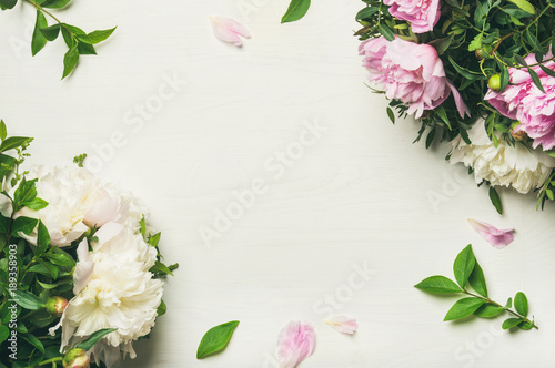 Spring floral layout with flowers. Flat-lay of tender pale pink and white peonies over white background, top view, copy space. Womens day, Valentines or lovers day greeting card or wedding invitation