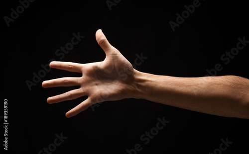 Male hand shows number five isolated at black