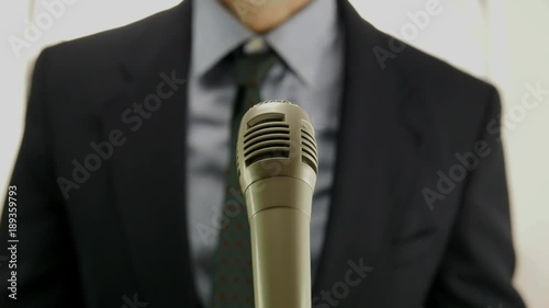 out of focus man speaking in front of microphone