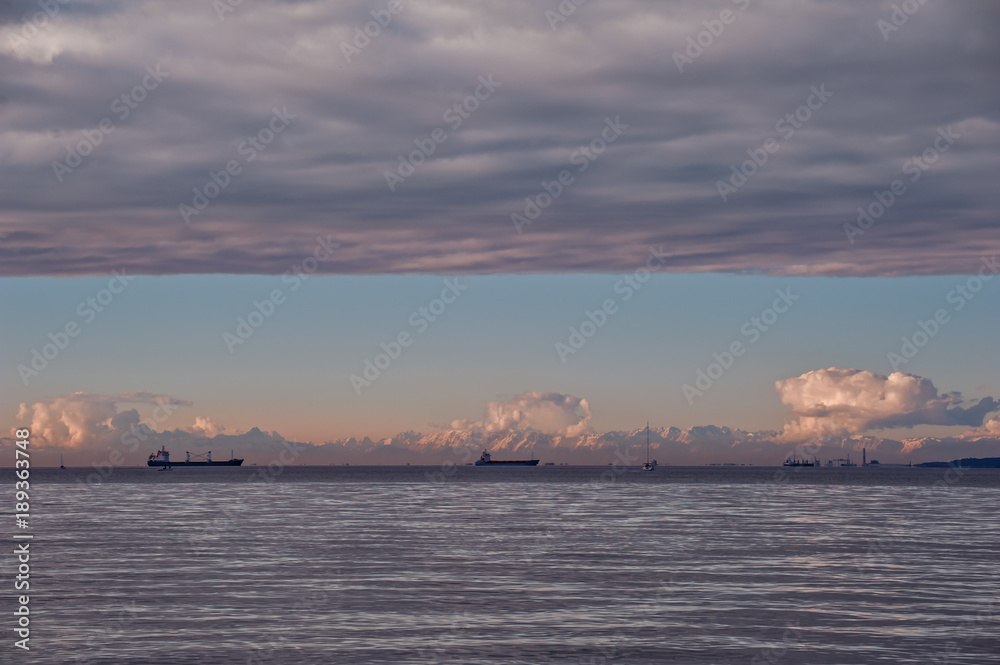 Seascape with ship at sunset with sky overcast .
