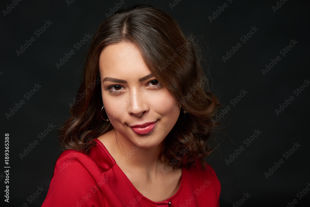 Closeup portrait of beautiful brunette woman in red shirt and wavy hair, over dark background Closeup portrait of beautiful brunette woman in red shirt and wavy hair, over dark background
