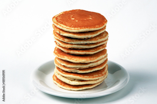 Tall stack of pancakes set against a white background