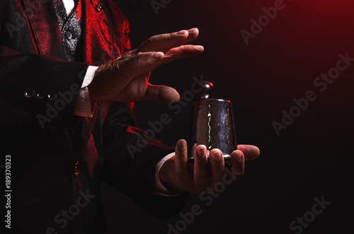 Magician shows trick with a metal cup. Manipulation with props. Sleight of hand.
