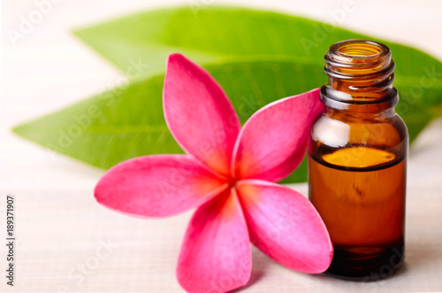 Plumeria Essential Oil Perfume and red plumeria flowers on the wooden table
