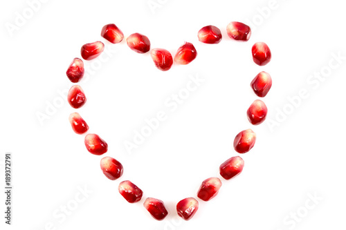 Fresh raw seeds of pomegranate fruit with heart symbol isolated on white background, Heart symbol made from seeds of pomegranate fruit on white background, with clipping path