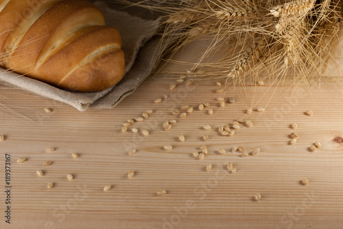 Rustic delicious aromatic fresh baguette  loaf and wheat on wooden table copyspace text space. baking  ingredients  cooking pastry diet healthy nutrition shop store produce