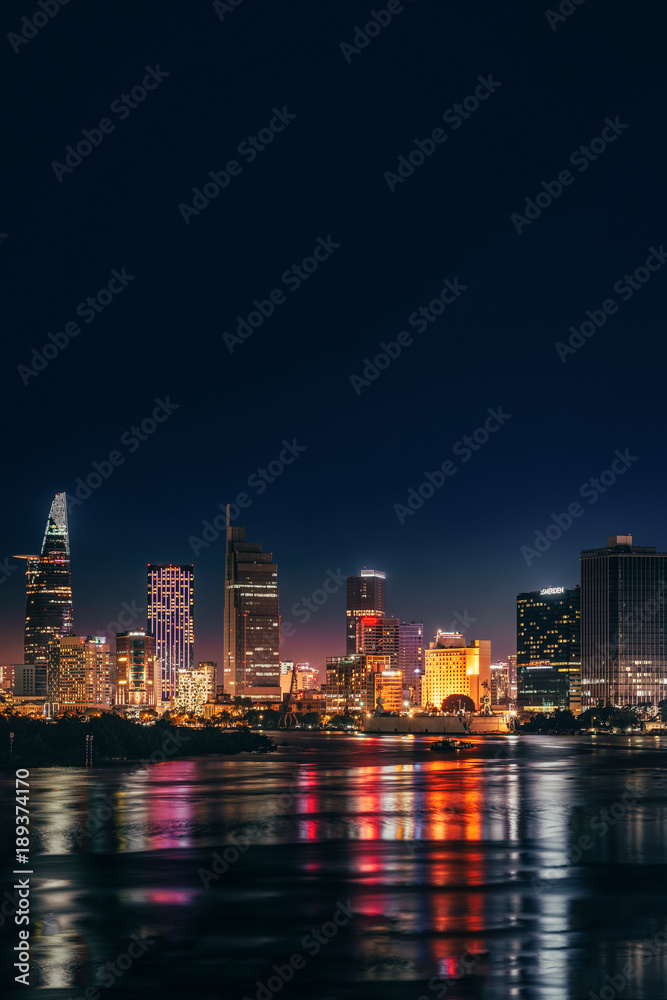 HO CHI MINH, VIETNAM - NOVEMBER 22, 2017: Urban night skyline view of Ho Chi Minh city. Front view on colored skyscrapers in downtown from the river.