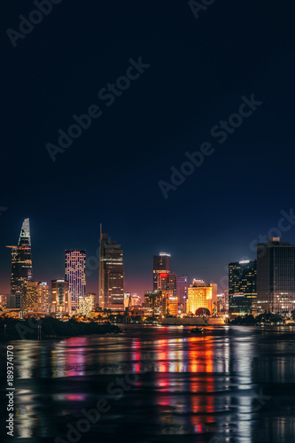 HO CHI MINH  VIETNAM - NOVEMBER 22  2017  Urban night skyline view of Ho Chi Minh city. Front view on colored skyscrapers in downtown from the river.