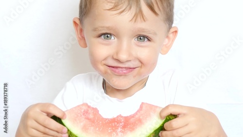 Boy child sitting at table with pleasure eating watermelon on white background, close-up - 2