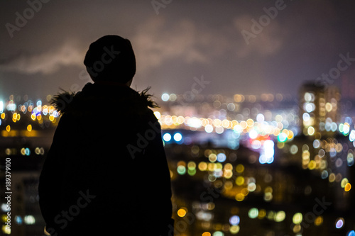 man stands on the roof and looks at the night city