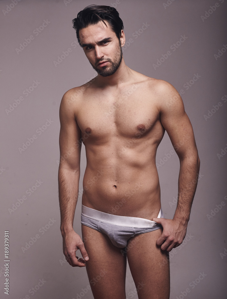 one young handsome man, looking at camera, shirtless, fashion model, gray background wearing briefs. one young handsome man, looking at camera, shirtless, fashion model, gray background wearing briefs.