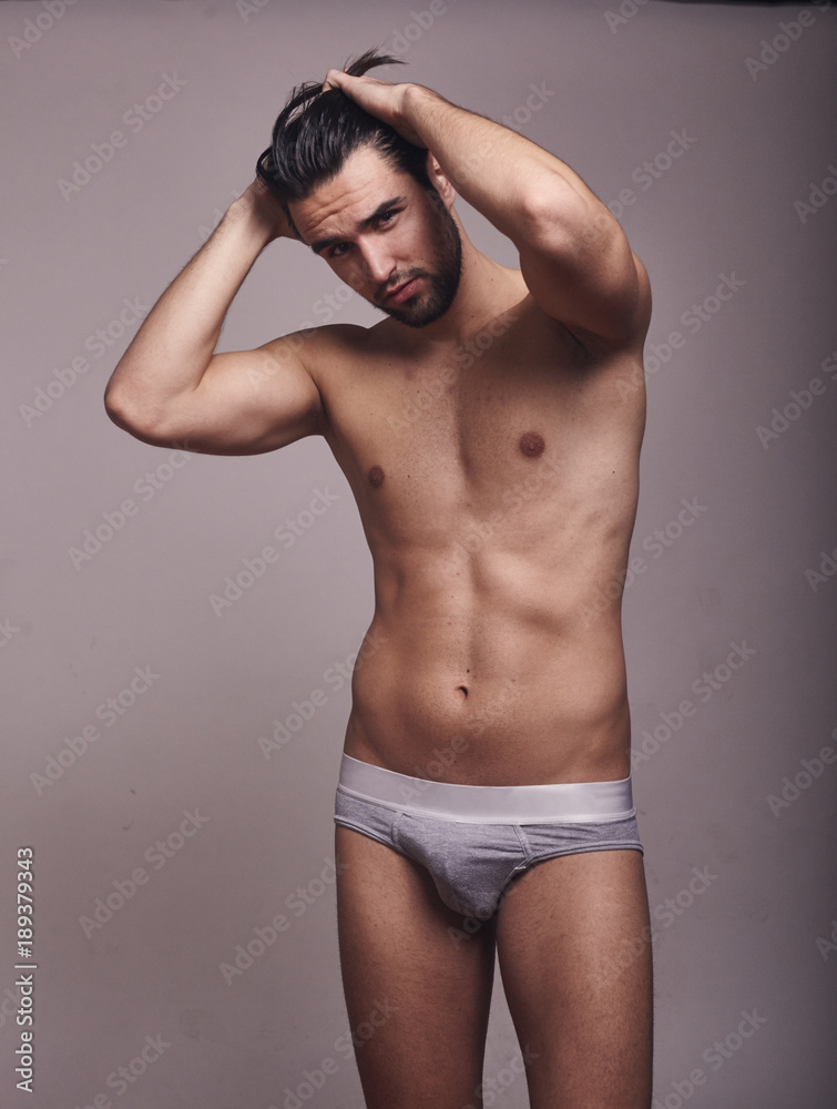 one young handsome man, looking at camera, shirtless, fashion model, gray background wearing briefs. one young handsome man, looking at camera, shirtless, fashion model, gray background wearing briefs.