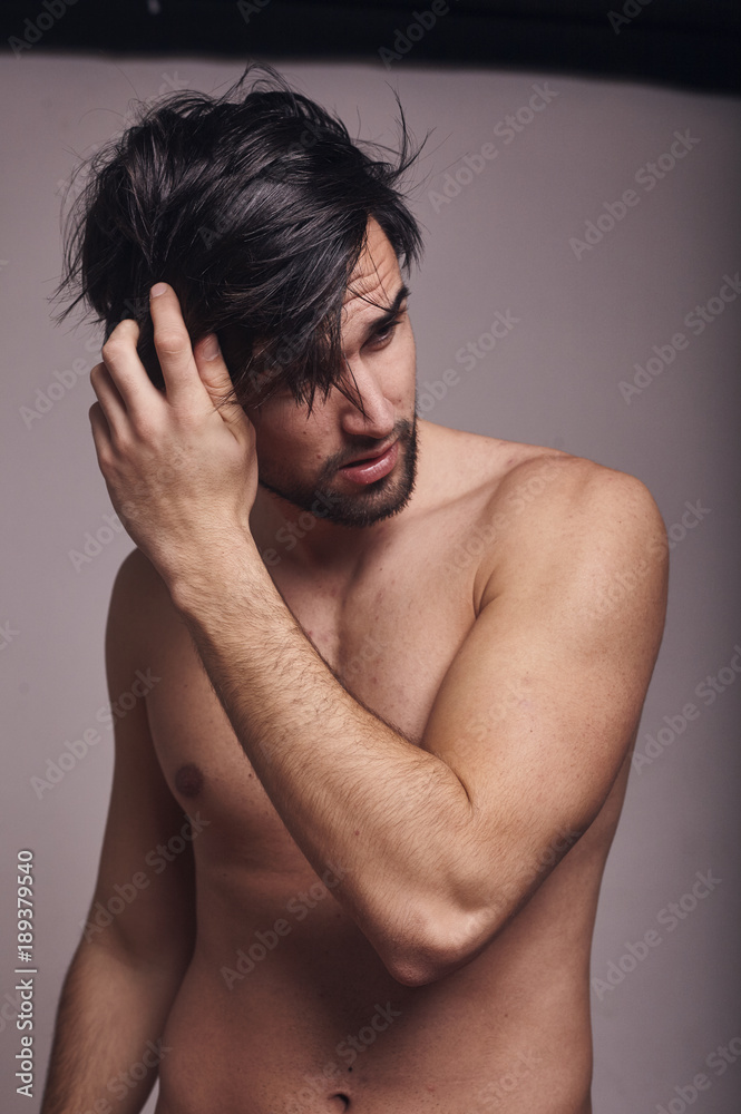 one young man shirtless, messing with his hair, looking away from camera. one young man shirtless, messing with his hair, looking away from camera.