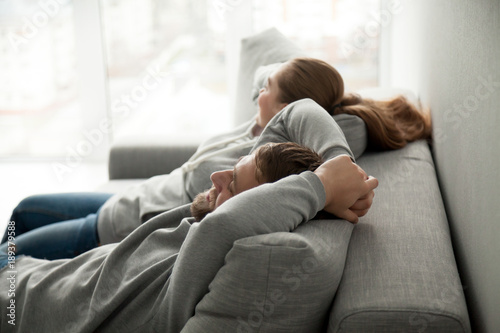 Billede på lærred Relaxed couple asleep resting or having nap sitting on comfortable sofa enjoying