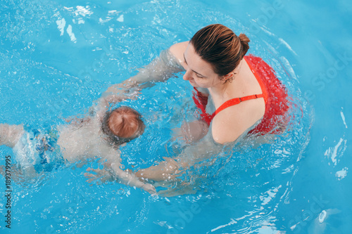 White Caucasian mother traning her newborn baby to float in swimming pool. Baby diving in water. Healthy active lifestyle. Family activity and early development concept © anoushkatoronto