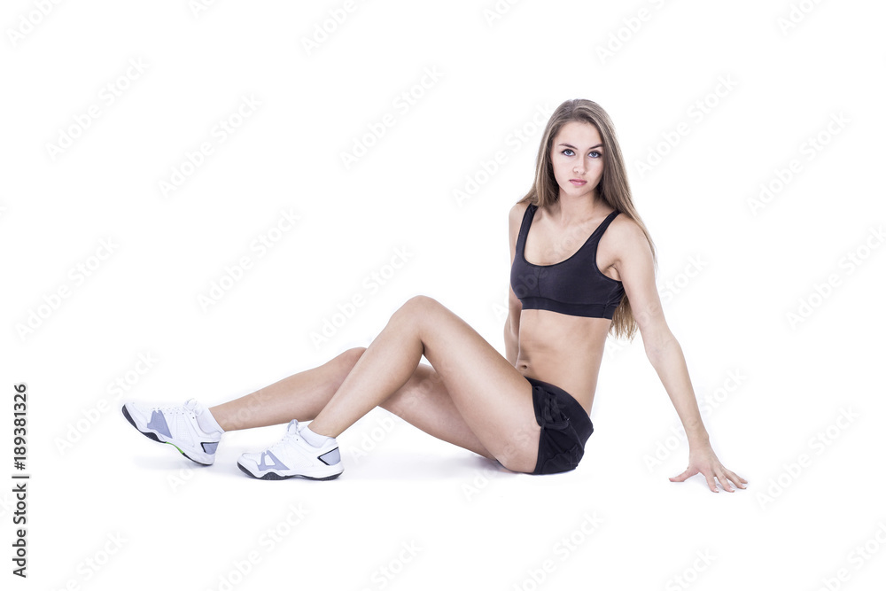 young female fitness instructor in a training suit sitting on the floor in the gym young female fitness instructor in a training suit sitting on the floor in the gym