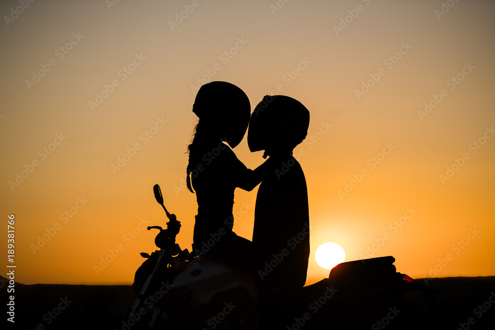 silueta de pareja encima de la moto con sol detras Stock Photo | Adobe Stock