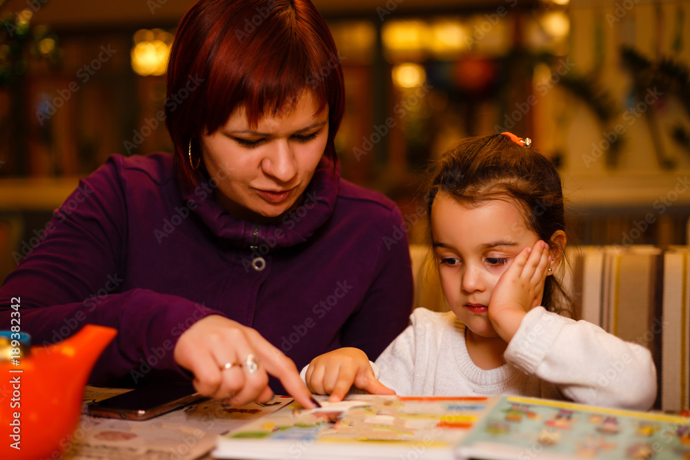 Fototapeta premium mother and daughter in a cafe read a book