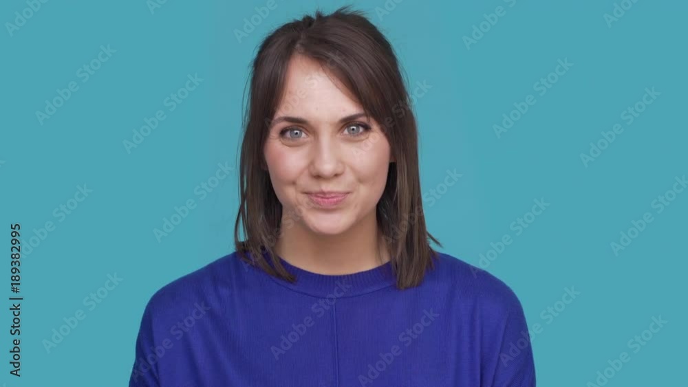 Portrait of cute woman smiling with white perfect teeth saying yes and nodding positively meaning agreement over blue background. Concept of emotions Portrait of cute woman smiling with white perfect teeth saying yes and nodding positively meaning agreement over blue background. Concept of emotions