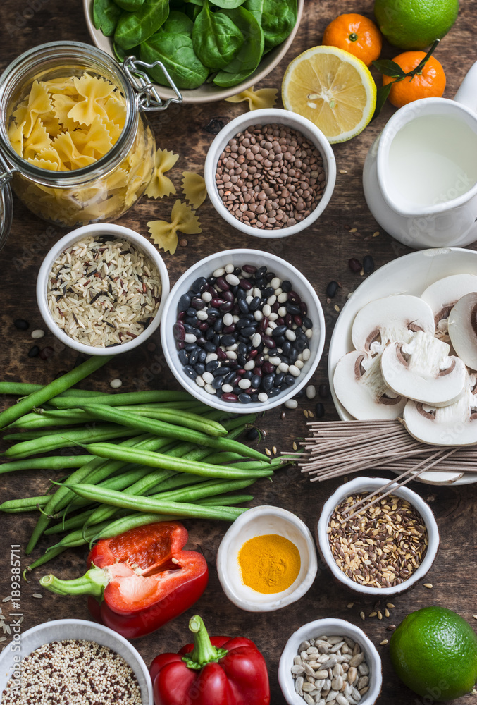 Vegetarian food set of products - cereals, vegetables, fruit, pasta, seeds on a brown wooden background, top view. Healthy food concept