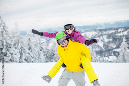 Young couple in snowboarding clothes having fun during the winter vacation on the snowy mountains